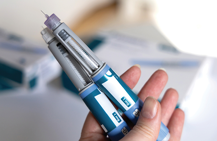 A person's handing holding two blue-and-white syringes
