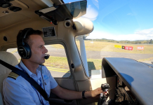 Pilot in a light aircraft cockpit at a controlled aerodrome, wearing a headset and preparing for taxi, with the runway visible ahead.