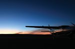 In the realm of the senses A plane is parked on the ground with a sunset behind it.