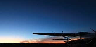 A plane is parked on the ground with a sunset behind it.