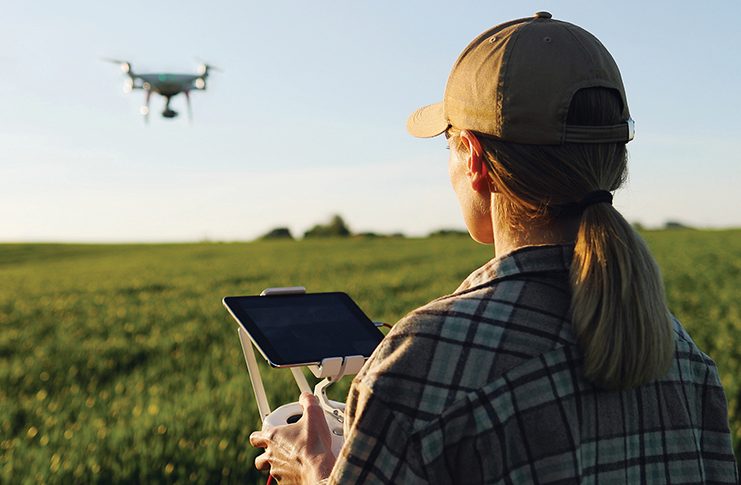 A woman flying a drone over a field