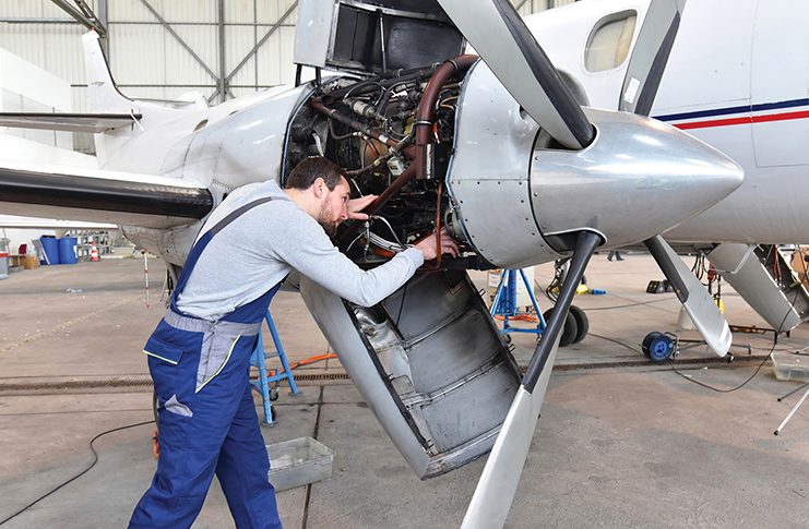 A maintenance engineer examines an aeroplane's engine