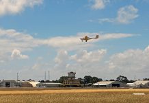 An aeroplane flying over the runway of an airport