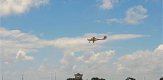 An aeroplane flying over the runway of an airport