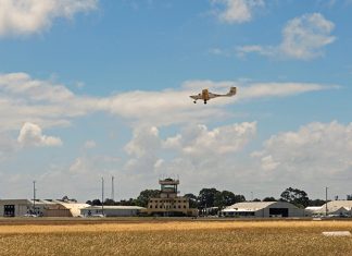 An aeroplane flying over the runway of an airport