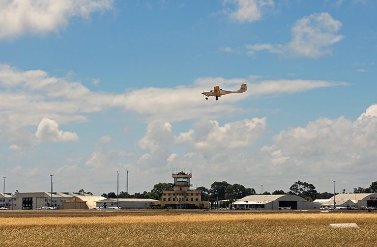 An aeroplane flying over the runway of an airport