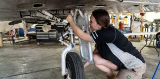 Female aircraft maintainer working on a Piper PA-31 aircraft.