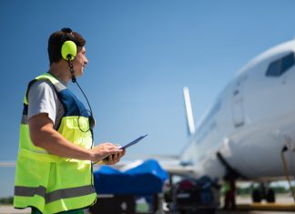 Paperwork won’t keep you safe Side view of airport worker in a high visibility vest looking at passenger plane.