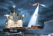A helicopter hovers above a ship at night, as a light beams down and someone descends on a rope