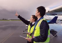 Future tense Two people in high visibility jackets with aeroplanes behind them