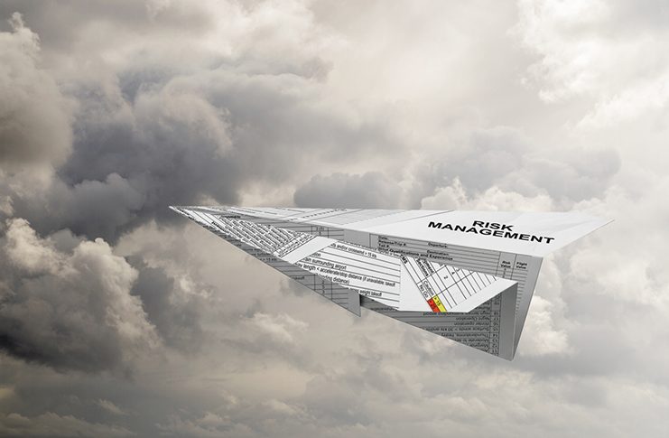 A paper aeroplane made from a risk management form flies through a cloudy sky